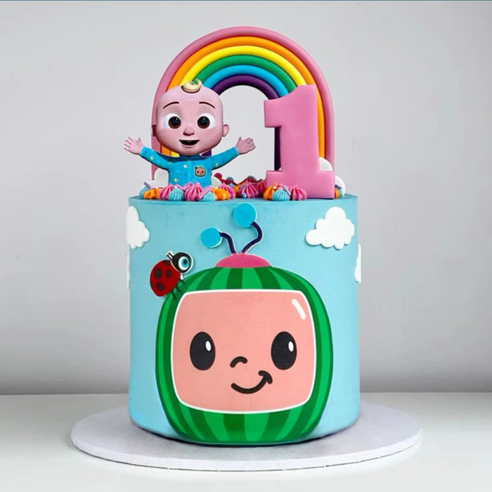 Colorful 1st birthday cake with Cocomelon theme, rainbow, and smiling watermelon face design