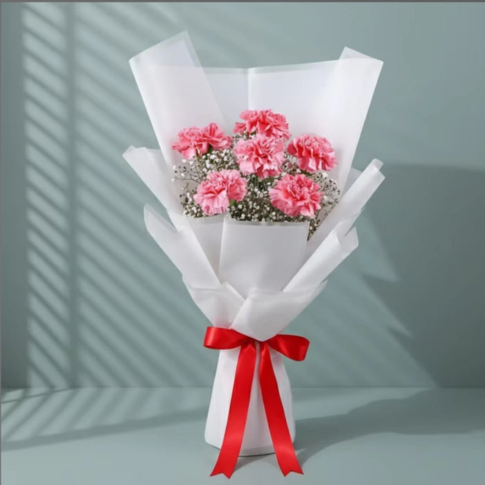 Pink carnations flower bouquet with white baby's breath wrapped in white paper