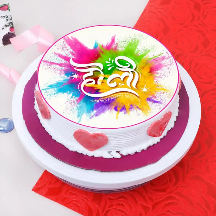 Decorated Holi Festive Cake with white frosting, pink heart accents, colorful splash design, for celebrations