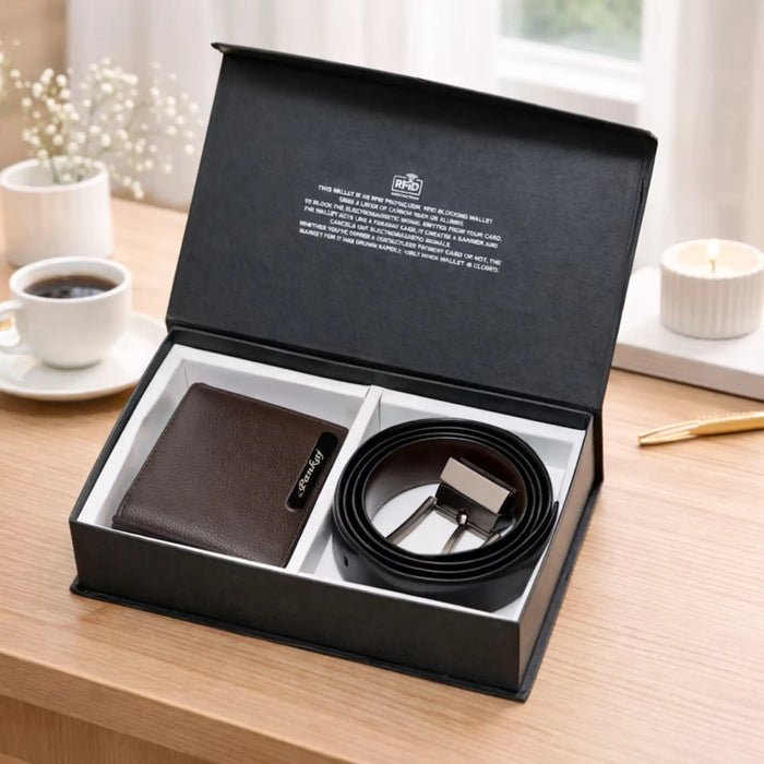 Brown wallet and black belt set in a black box on a wooden table with a cup of coffee and a plant in the background.