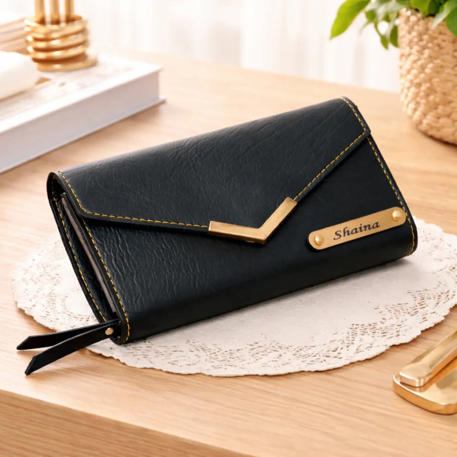 Black wallet with gold accents on a wooden surface, featuring the brand 'Sobia'.