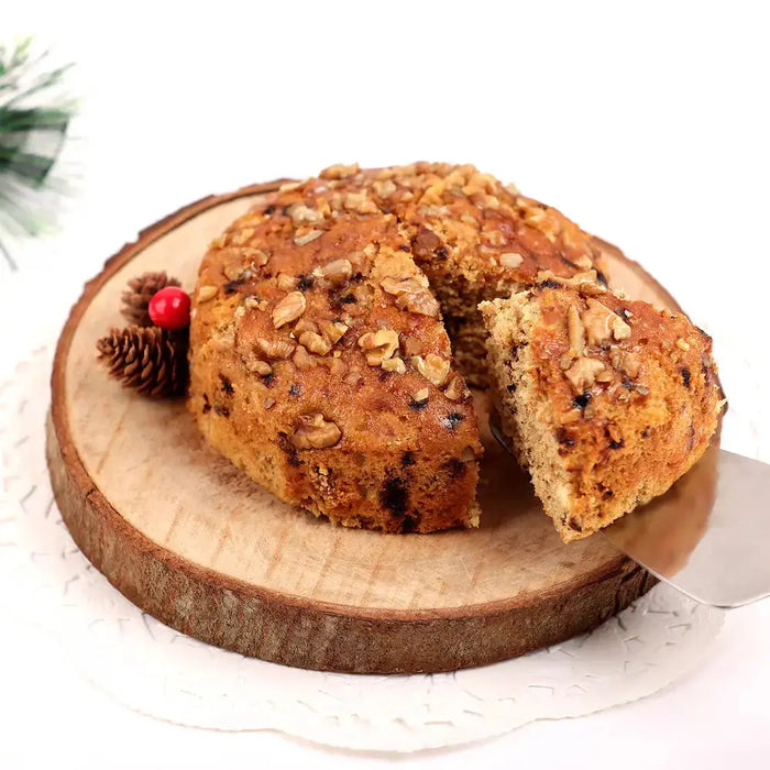 Vanilla Walnut Dry Cake in Tin - 300gm sliced on wooden board, showcasing rich texture and nut topping, ideal for festive gifting.