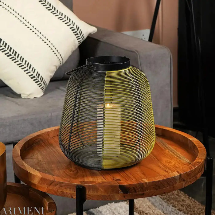 Wanderer Candle Holder Iron Black - 29cm x 33cm x 29cm placed on a wooden coffee table in a modern living room, showcasing its stylish wireframe design.